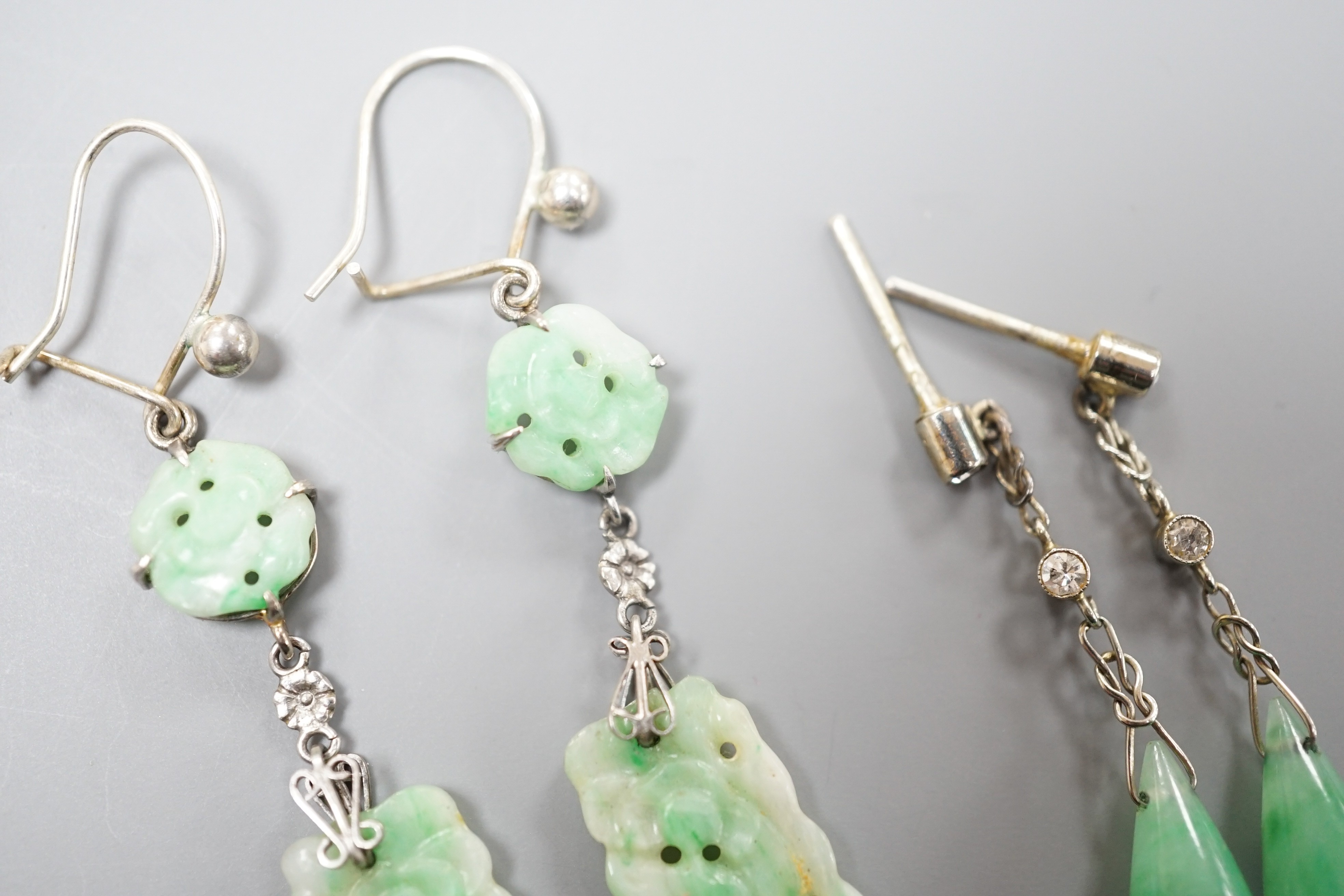 A pair of white metal pair shaped jade and two stone diamond set drop earrings, 37mm and one other pair of carved jade drop earrings, gross weight 8 grams.